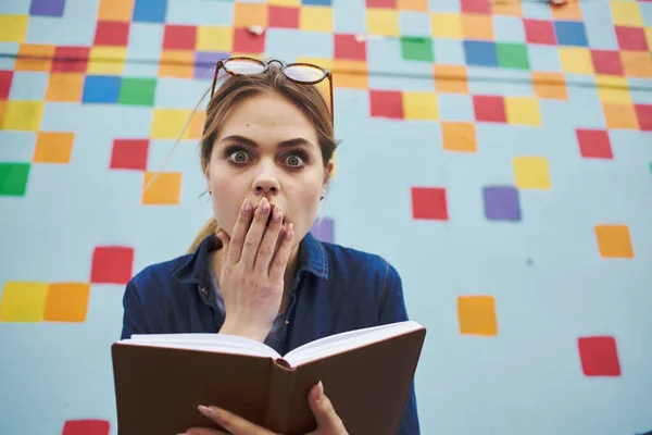 Livre étudiant femme en main modèle d'émotions et mur multicolore — Photo
