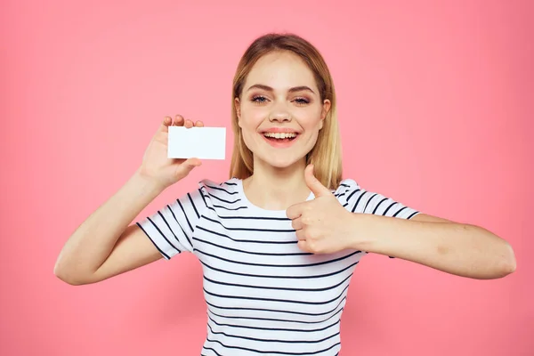 Donna con un biglietto da visita in mano una t-shirt a righe sfondo rosa Copia Spazio pubblicità — Foto Stock