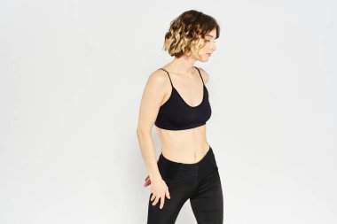 Hafif arka planda taytlı ince kadın jimnastik yapıyor.