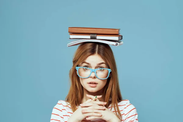 Vrouwelijke student met boeken op haar hoofd wetenschap onderwijs blauwe achtergrond emoties gebaren met handen — Stockfoto