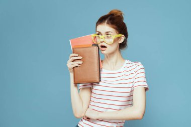Mavi arka plan ve sarı gözlük modeli saç kesimi üzerine kitapları olan bir kız öğrenci.
