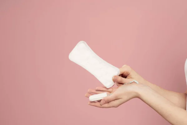 Skyddande pad och tampong i kvinnliga händer på en rosa bakgrund menstruation kritiska dagar — Stockfoto