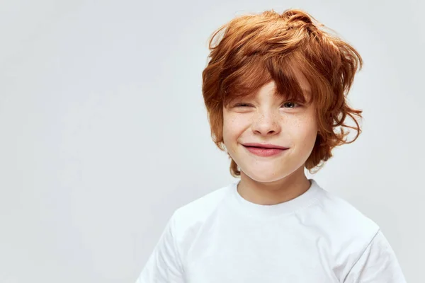 Sly garçon aux cheveux roux avec les yeux étroits conçu quelque chose de mauvais t-shirt blanc vue recadrée — Photo