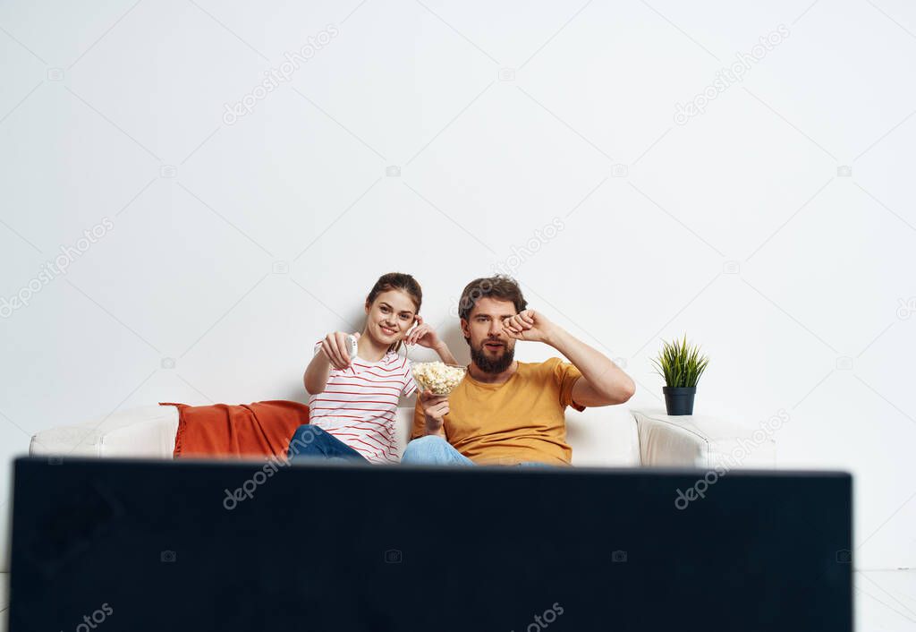 man and woman on the couch watching tv flower potted