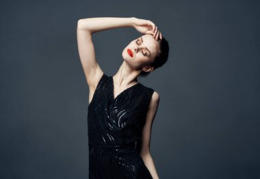 Siyah elbiseli enerjik bir kadın elleriyle jestler yapar. Duygular sürpriz zevk verir.