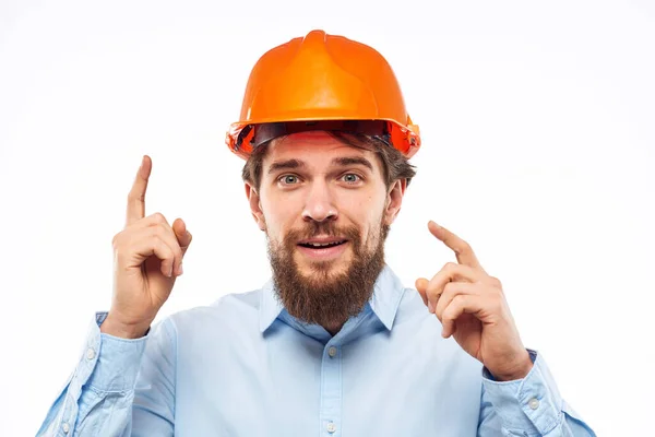 Um homem gesticula com as mãos um engenheiro laranja duro chapéu construção de segurança — Fotografia de Stock