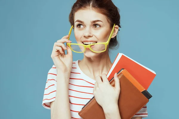 Női diák könyvekkel a kezében a kék háttér és a sárga szemüveg modell frizura vágott kilátás — Stock Fotó