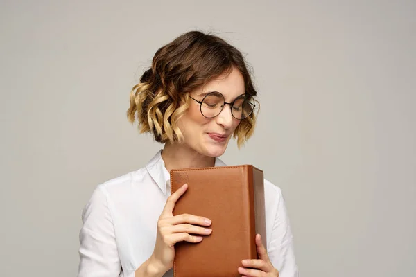 Frau mit Notizblock in den Händen Geschäftsarbeit beige Hintergrund Brille Frisur — Stockfoto