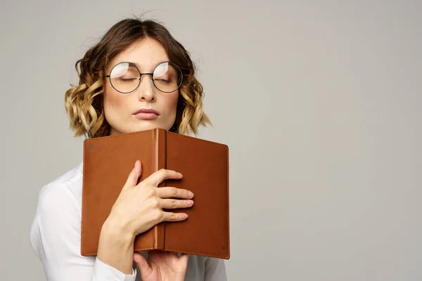 Vrouw met notitieblok in handen zakelijke werk beige achtergrond bril kapsel — Stockfoto