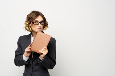 Not defteri ve gözlüklü bir iş kadını takım elbise modelinin hafif arka planında çalışıyor..