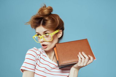 Okul müdürünün mavi arka planında not defterleri ve gözlüklü saç stili olan kız öğrenci.