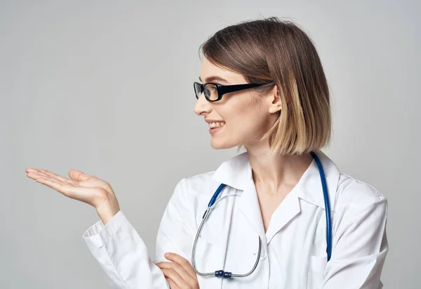 Médico con un estetoscopio muestra su mano a un lado sobre un fondo gris Copiar espacio —  Fotos de Stock