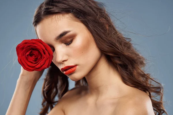 Portrét ženy s červenou růží v rukou na šedém pozadí nahá ramena večerní make-up — Stock fotografie