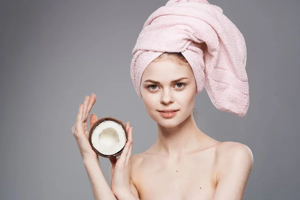 Donna con spalle nude con una noce di cocco nelle sue mani pelle pulita Cosmetici naturali esotici sfondo grigio — Foto Stock