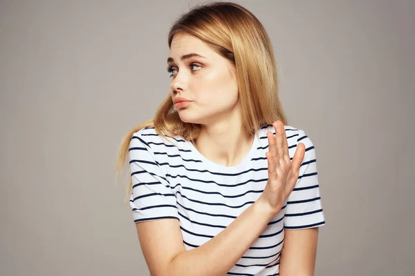 Una donna con un'espressione dispiaciuta sta gesticolando con le mani T-shirt sfondo grigio — Foto Stock