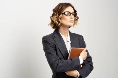 Klasik takım elbiseli bir iş kadını elinde bir not defteri ve yüzünde gözlüklerle.