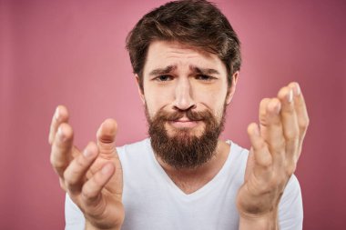Beyaz tişörtlü duygusal sakallı adam hoşnutsuz pembe arka plan