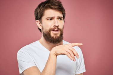 Beyaz tişörtlü duygusal sakallı adam hoşnutsuz pembe arka plan