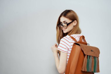 Sırtında not defteri ve sırt çantası olan bayan öğrenci bilim gözlüklerini kırpmış.