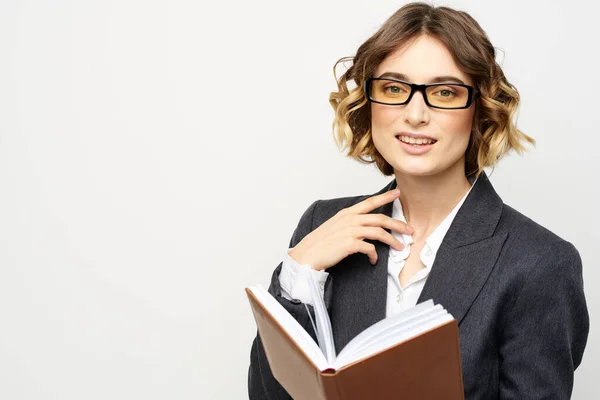 Жінка на роботі з книгою на світлому фоні класичний костюм окуляри голова — стокове фото