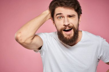 Beyaz tişörtlü adam elleriyle jest yapıyor. Duyguları var. Pembe arka plan eğlenceli.