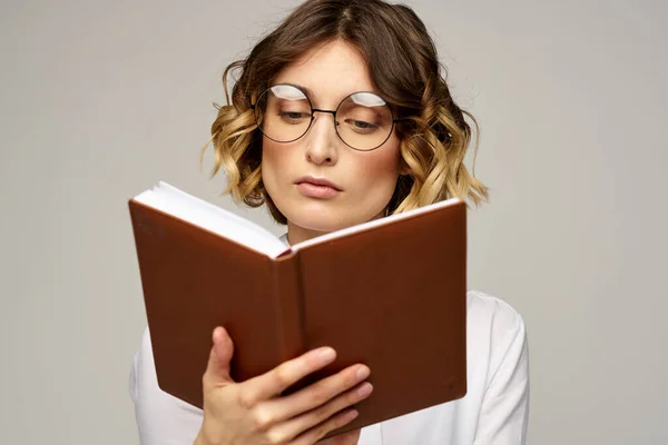 Femme d'affaires avec bloc-notes et lunettes sur un fond clair coiffure succès émotions — Photo