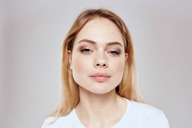 Beyaz tişörtlü neşeli sarışın kadın arka planda kırpılmış.