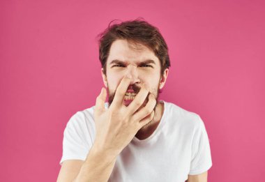 Sakallı bir adam pembe bir arka planda elleri yüzüne yakın hareket eder.