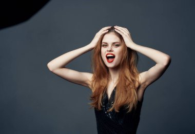 Gri arka planda fevri bir kadın. Kızgın görünüyor. Manken ve siyah elbise.