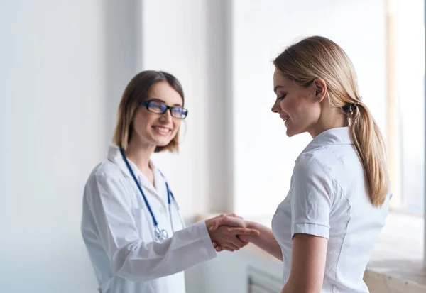 Vrouw arts schudt handen met patiënt in wit t-shirt — Stockfoto