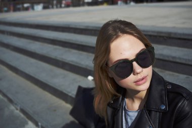 Kadın model, sonbaharda caddede binanın yanındaki merdivenlerde oturuyor.