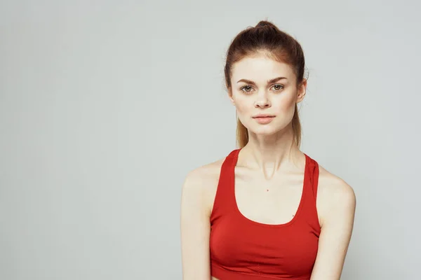 Een vrouw in een rood T-shirt op een lichte achtergrond is bezig met fitness gebaren met haar handen een slank figuur dieet — Stockfoto