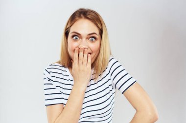 Çizgili tişörtlü duygusal kadın, elleri yaşam tarzı hafif arka planlı.