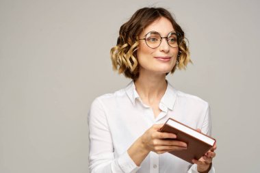 Elinde not defteri olan kadın iş hayatında bej arka plan gözlüklü saç stili.