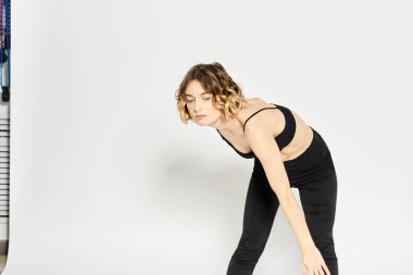 Hafif arka planda taytlı ince kadın jimnastik yapıyor.