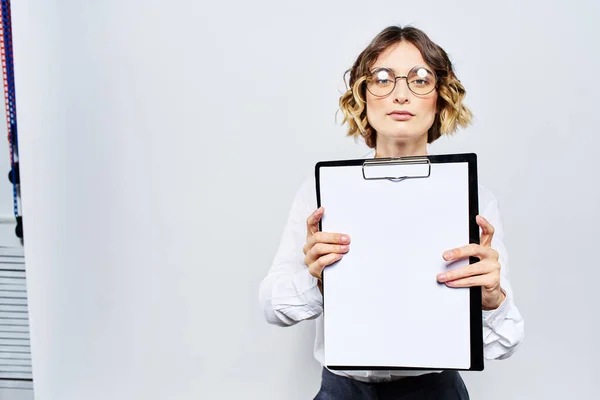 Geschäftsfrau mit einem Ordner weißer Dokumente in der Hand auf hellem Hintergrund und Frisur Brillenmodell — Stockfoto