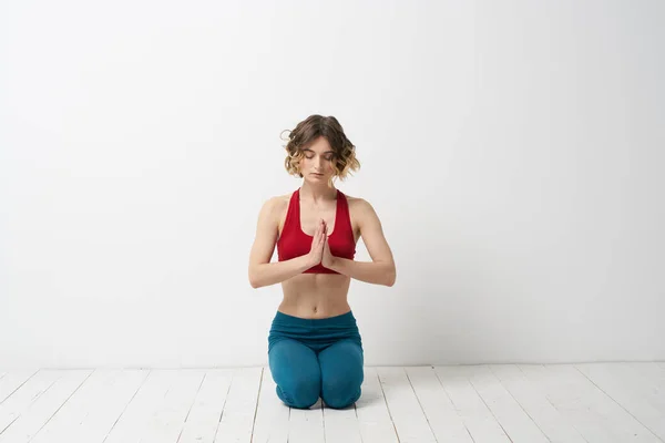 一位穿蓝色牛仔裤的妇女在室内浅色的背景下练习瑜伽，一位体形纤细的体操运动员在室内练习瑜伽 — 图库照片