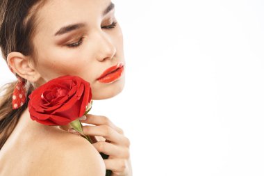 Yüzünde kırmızı gül olan güzel bir kadın çıplak omuz portresi.