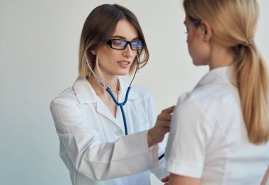 Steteskoplu mutlu kadın doktor ve kadın hastanın kapalı alanlara bakışı