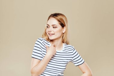 Şirin, sarışın, çizgili tişörtlü, gülümseyen, bej renkli stüdyo arka planı.