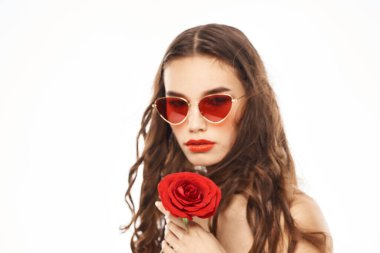 Kırmızı gül ve güneş gözlüklü, çıplak omuzlu esmer kız.