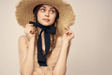 Bej elbiseli, hasır şapkalı, siyah kurdele takmış, manken görünümlü romantik bir kız.