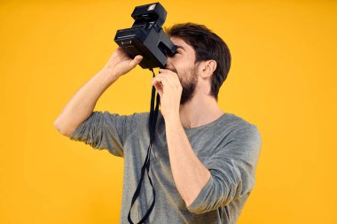 Profesyonel fotoğraf makinesi olan bir erkek fotoğrafçı. Profesyonel Yaratıcı yaklaşım stüdyo sarı arka plan