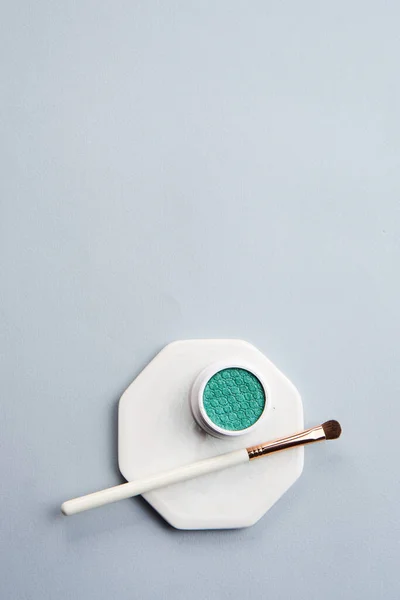 Sombra de olhos verde e pincel de maquiagem no fundo isolado do suporte branco — Fotografia de Stock