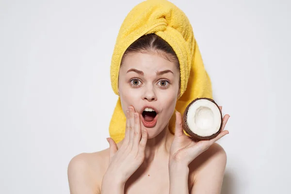 Kvinna med bara axlar med kokos i händerna gul handduk på huvudet ren hudvård — Stockfoto