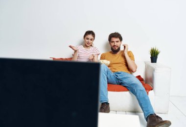 Erkek ve kadın kanepede oturmuş televizyon seyrediyor.