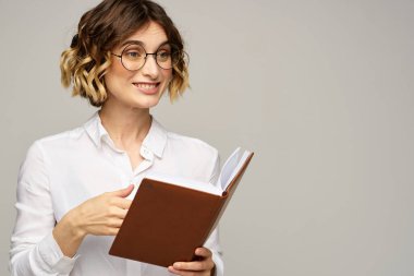 Elinde not defteri olan kadın iş hayatında bej arka plan gözlüklü saç stili.