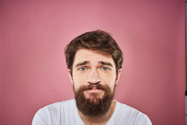 Pria berjanggut dengan kaos putih emosi ekspresi wajah tidak senang Studio merah muda latar belakang — Stok Foto
