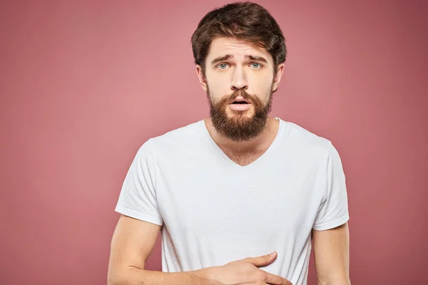 Pria emosional t shirt putih ekspresi wajah sedih latar belakang merah muda — Stok Foto