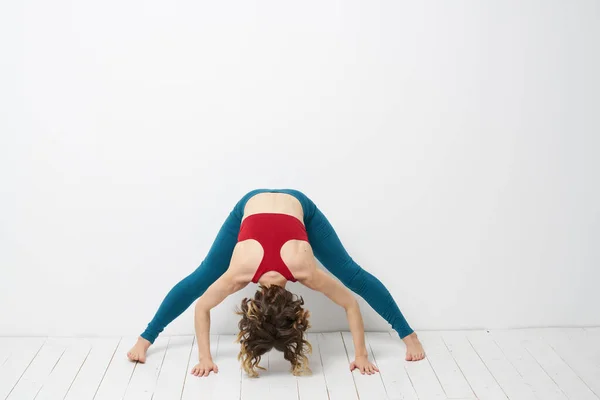 Femme sportive dans une salle lumineuse faisant du yoga en legging bleu pleine croissance et un débardeur rouge — Photo